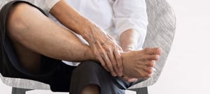 Un uomo con bruciore interno alla caviglia, che potrebbe essere causato da una sindrome del tunnel tarsale.