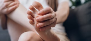 Foto di una donna che si massaggia le dita dei piedi intorpidite.