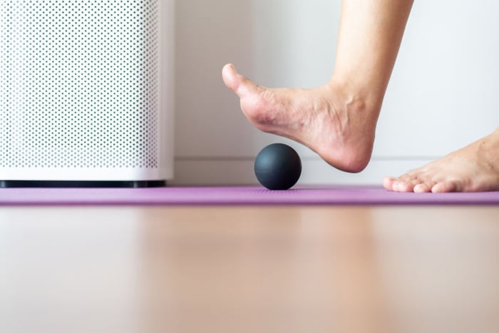 Foto di un esercizio per la fascia plantare svolto su un tappetino con una pallina di gomma.