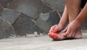 Un uomo con neuropatia ai piedi si massaggia l'alluce.