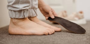 Foto di una persona che si appresta a indossare un plantare ortopedico.