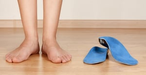 Foto di una donna in piedi accanto a due plantari per alluce valgo.